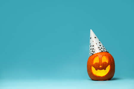 Carved pumpkin for Halloween in party hat on blue backgroundの写真素材