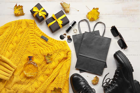 Stylish female clothes, gift boxes and paper bags on white wooden background. black friday saleの写真素材