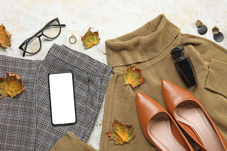 Stylish female clothes, accessories, dry leaves and mobile phone on light background. black friday...
