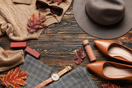 Frame made of trendy female accessories, clothes and dry leaves on wooden backgroundの写真素材