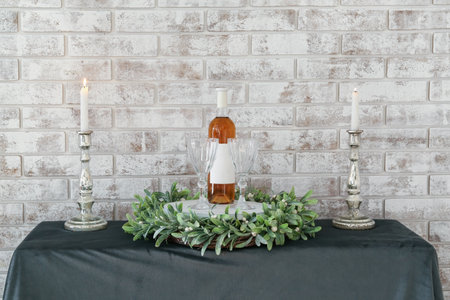 Dining table with candles, glasses and mistletoe wreath near brick wallの写真素材