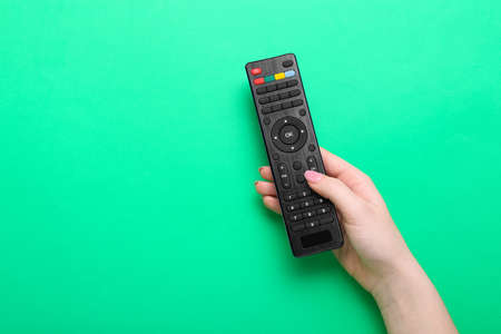 Woman holding TV remote controller on green backgroundの写真素材