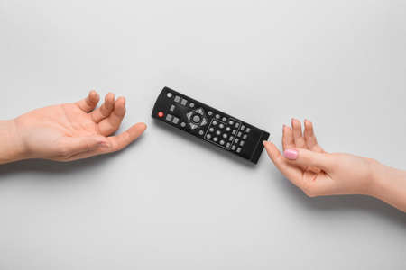 Female hands with TV remote controller on gray background