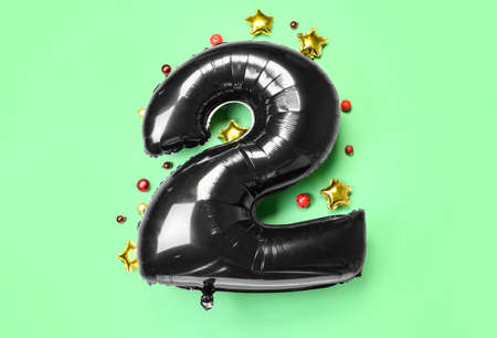 Black balloon in shape of figure 2 and Christmas balls on green backgroundの写真素材