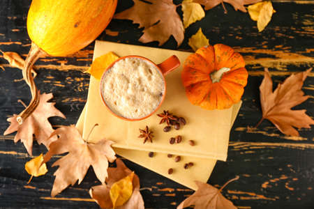 Beautiful autumn composition with cup of coffee, books and leaves on black wooden backgroundの写真素材