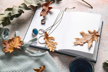 Blank book, cup of tea and autumn decor on light backgroundの写真素材