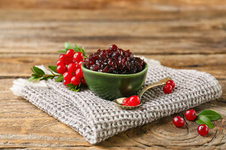 Bowl of tasty lingonberry jam and fresh berries on wooden backgroundの写真素材