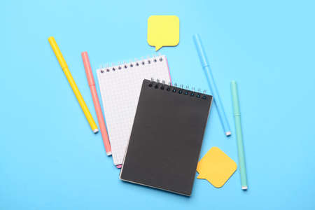 Notebooks, felt-tip pens and sticky note papers on color background