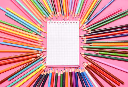 Composition with blank notebook and colorful pencils on color background