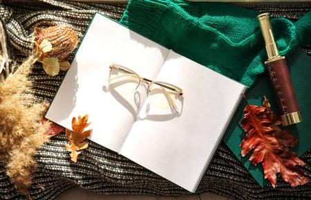 Blank book, eyeglasses and autumn decor on plaid