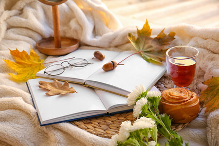 Books, eyeglasses, cup of tea and autumn decor on plaidの写真素材
