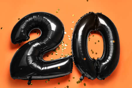 Figure 20 made of balloons and confetti on orange backgroundの写真素材