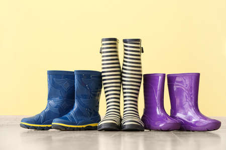 Different rubber boots on floor near color wallの写真素材