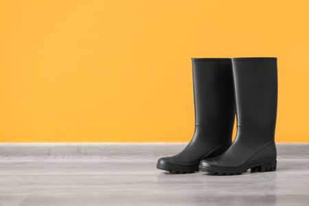 Pair of black rubber boots near color wallの写真素材