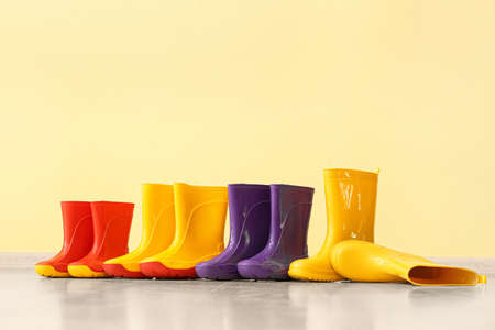 Many different rubber boots on floor near color wall
