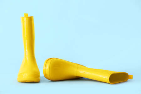 Pair of yellow rubber boots on color backgroundの写真素材