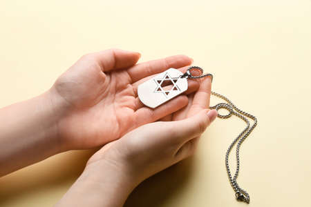 Hands with military tag of Israeli soldier on color background