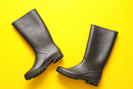 Pair of rubber boots on yellow backgroundの写真素材