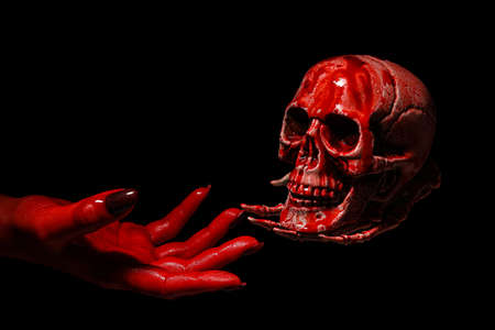 Hand and bloodstained human skull on black backgroundの写真素材