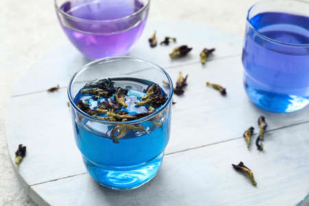 Wooden board with glasses of blue tea on light background, closeupの写真素材