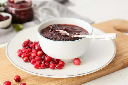Bowl with tasty lingonberry jam and fresh berries on white backgroundの写真素材