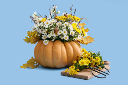Beautiful autumn bouquet in pumpkin on color backgroundの写真素材