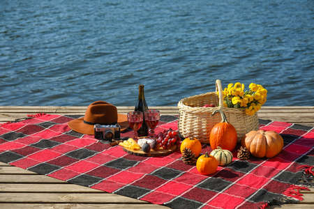 Tasty food with wine for romantic picnic near river on autumn day
