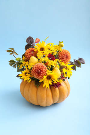 Beautiful autumn bouquet in pumpkin on color backgroundの写真素材