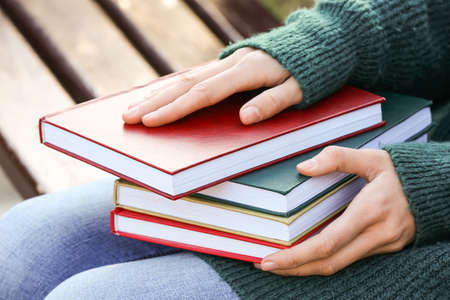 Woman with books on bench in autumn parkの写真素材