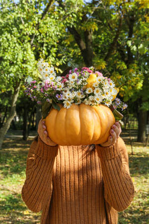 Woman holding beautiful bouquet of autumn flowers in pumpkin outdoorsの写真素材
