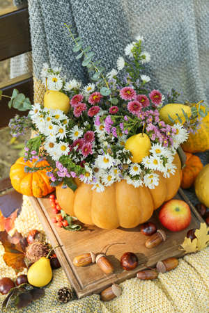 Beautiful bouquet of autumn flowers in pumpkin on bench outdoorsの写真素材
