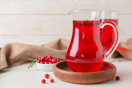 Jug of tasty lingonberry tea on tableの写真素材