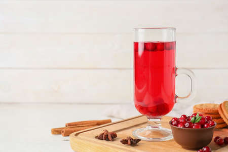 Board with glass of tasty lingonberry tea, berries and cookies on light wooden backgroundの写真素材