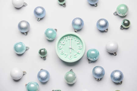 Composition with alarm clock and Christmas balls on light background
