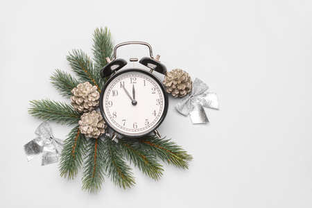 Christmas composition with alarm clock and fir branches on light background