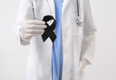 Doctor with black ribbon on light background. melanoma conceptの写真素材