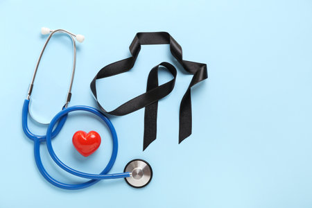 Black ribbon, stethoscope and heart on blue background. melanoma conceptの写真素材