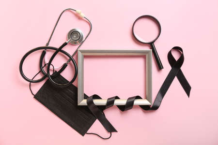Frame with black ribbon, stethoscope and magnifier on color background. melanoma concept