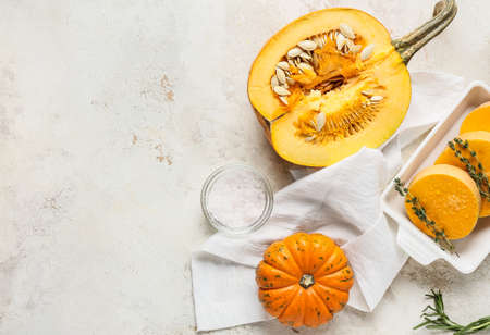 Baking dish with fresh pumpkin pieces and whole vegetable on light backgroundの写真素材
