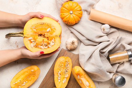 Female hands with fresh pumpkin pieces on light backgroundの写真素材