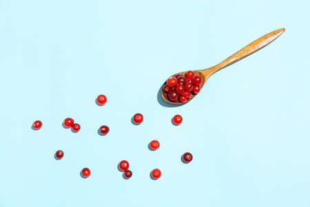 Spoon with ripe lingonberry on blue backgroundの写真素材