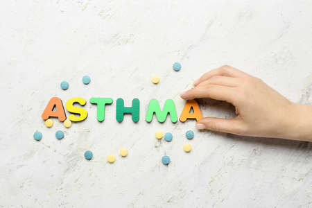 Female hand, pills and word ASTHMA on light backgroundの写真素材