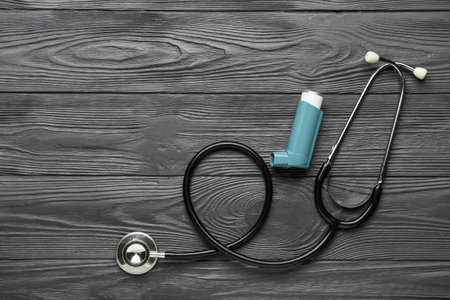 Asthma inhaler and stethoscope on dark wooden backgroundの写真素材