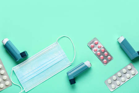 Asthma inhaler, medical mask and pills on color backgroundの写真素材