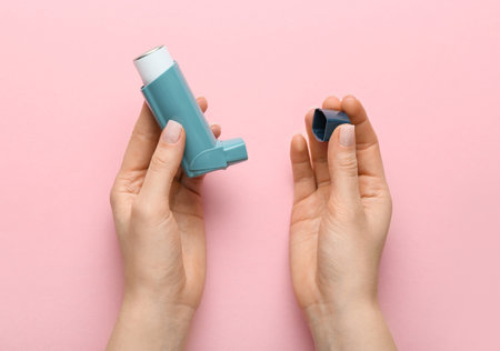 Female hands with modern asthma inhaler on color backgroundの写真素材