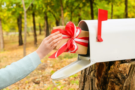Woman gift into mailbox in autumn parkの写真素材