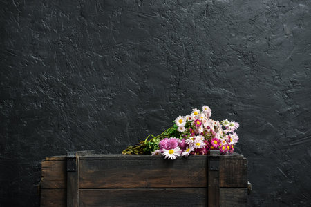 Beautiful flowers on wooden chest of drawers near dark wallの写真素材