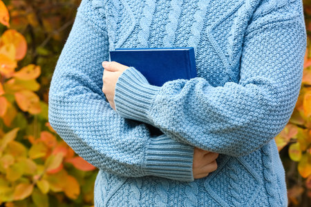 Woman holding book in autumn park, closeupの写真素材