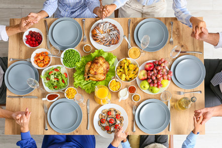 Thanksgiving Day. People praying and holding hands together at festive served tableの写真素材