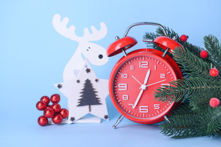 Christmas composition with alarm clock and fir branch on blue backgroundの写真素材